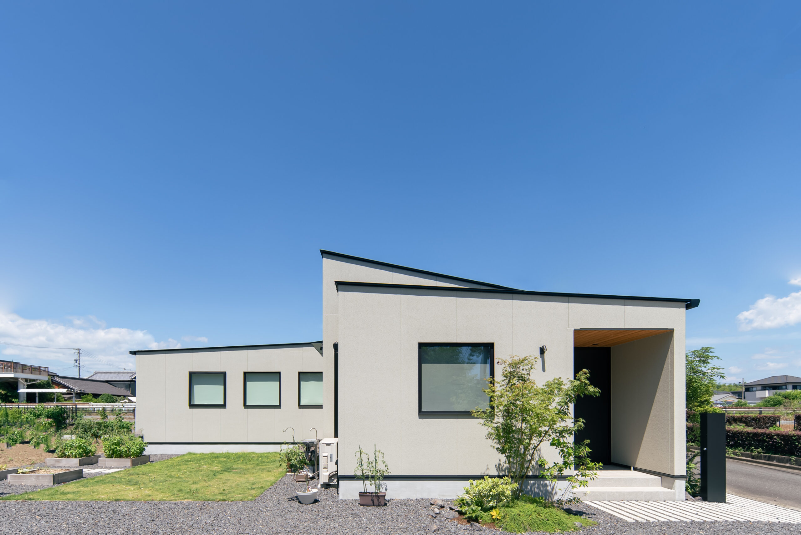 庭と畑を囲むL型の平屋の外観